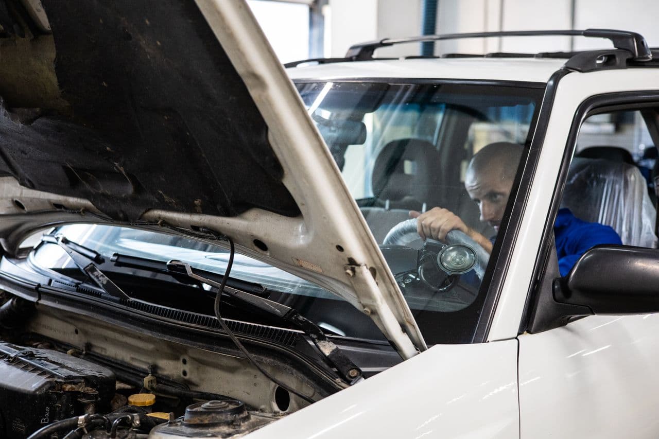 Un professionnel inspecte une voiture dans un atelier.