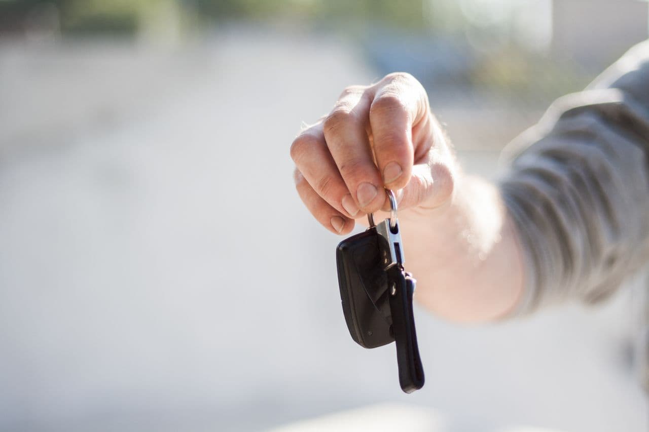 Une main remet les clés d’une voiture.