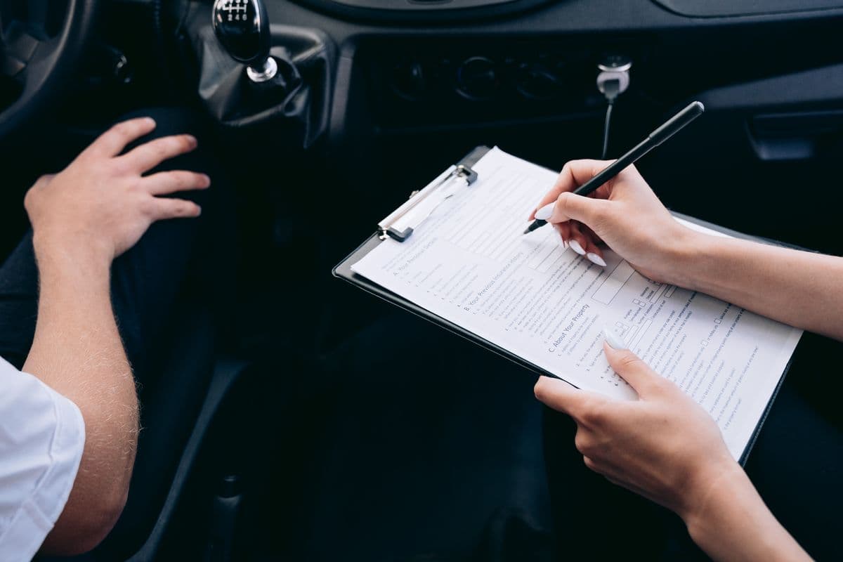 Une personne remplit un document à l’intérieur d’une voiture.